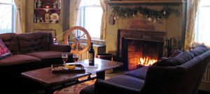 fireplace with fire light, wine bottle and glasses on table, spinning wheel in front of window
